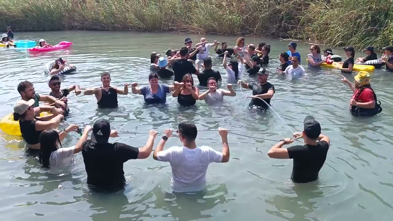 קבוצה בתוך הנהר עם ידיים באוויר